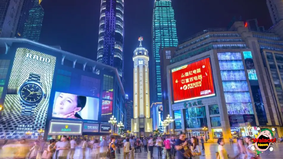 重庆解放碑步行街夜景，人群聚集在纪念碑广场，周围高楼林立与LED广告屏幕点亮全城