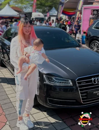 Kakak Saga怀抱孩子站在活动现场Audi轿车前合影
